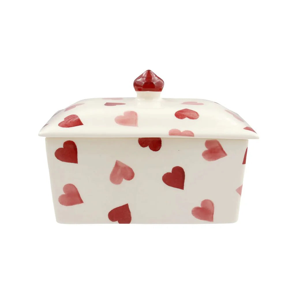 White ceramic butter dish with red heart patterns on a white background