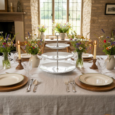 Three-tiered white serving tray with decorative metal stand on a white background