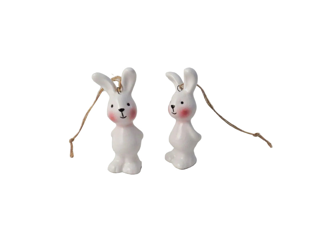 Two white ceramic bunny ornaments with pink accents on a light gray background