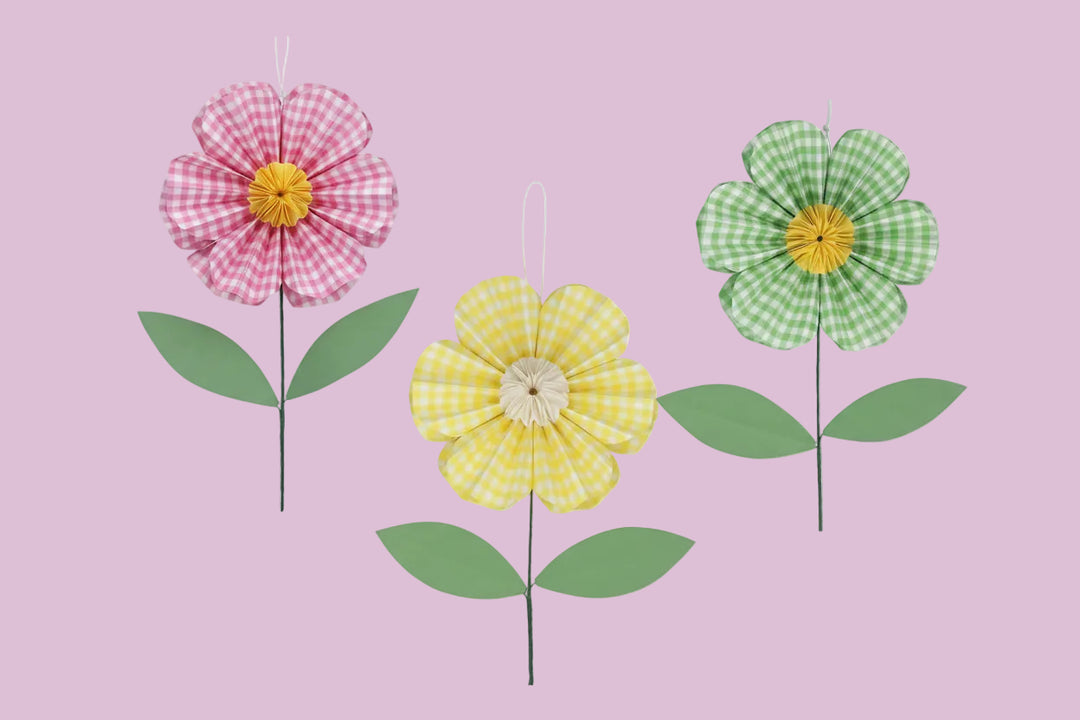 Three decorative flowers with checkered patterns and green stems, accompanied by their packaging on a white background.