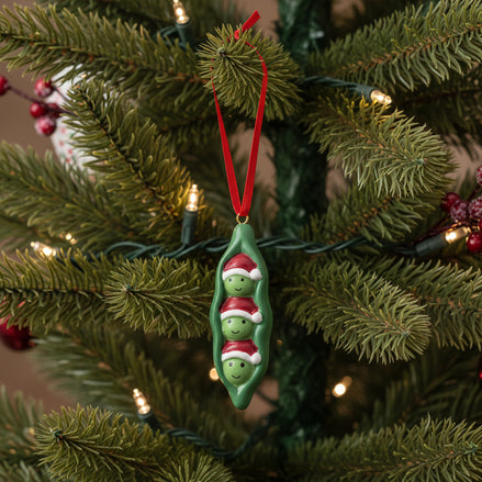 Decorative ornament shaped like a green pea pod with two smiling peas on a white background