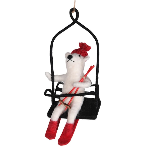 Decorative ornament of a polar bear on a ski lift with skis and a red hat.